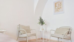 Une pièce au décor minimaliste, avec deux chaises en métal, une petite table blanche et un vase rempli de fleurs.