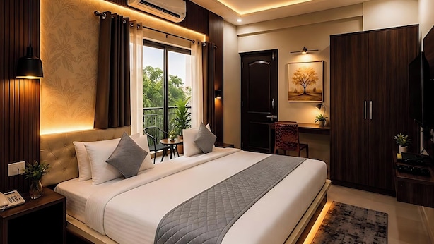 A modern hotel room with a large bed, a desk, a chair, a wardrobe, and a balcony with a view.