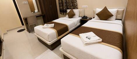 A hotel room with two beds, a desk, a mirror, and a wardrobe.