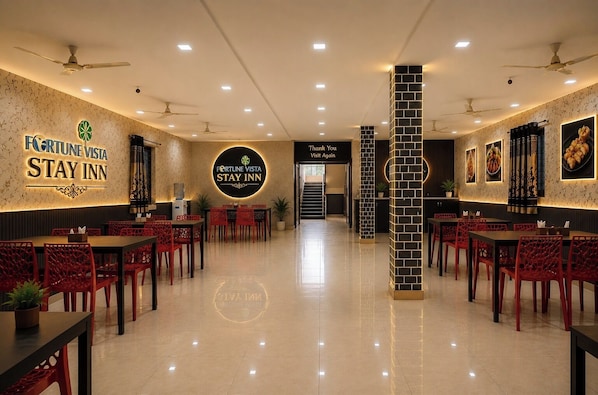 Eine Hotellobby mit einem runden zentralen Schild, roten Stühlen, Tischen und Deckenventilatoren.