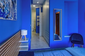 A modern bedroom with a bed, bedside table, lamp, and a mirror. - Posillipo Luxury House (Napoli)