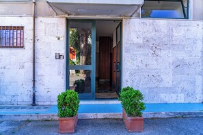 L'ingresso di un edificio con una porta in vetro, un cancello in metallo e due piante in vaso.