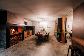 A modern kitchen with a built-in fireplace, dining area with chairs, and potted plants. - Villa AMore by Feel Croatia (Debeljak)