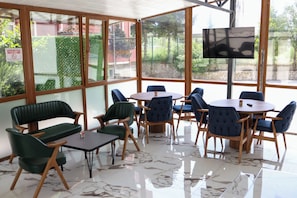 A room with a glass wall, a TV, and a table with chairs.
