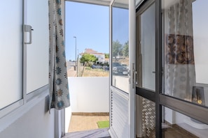 Ein Zimmer mit einer Schiebetür und einem Balkon, einem kleinen Fenster und einer Tür mit Griff.