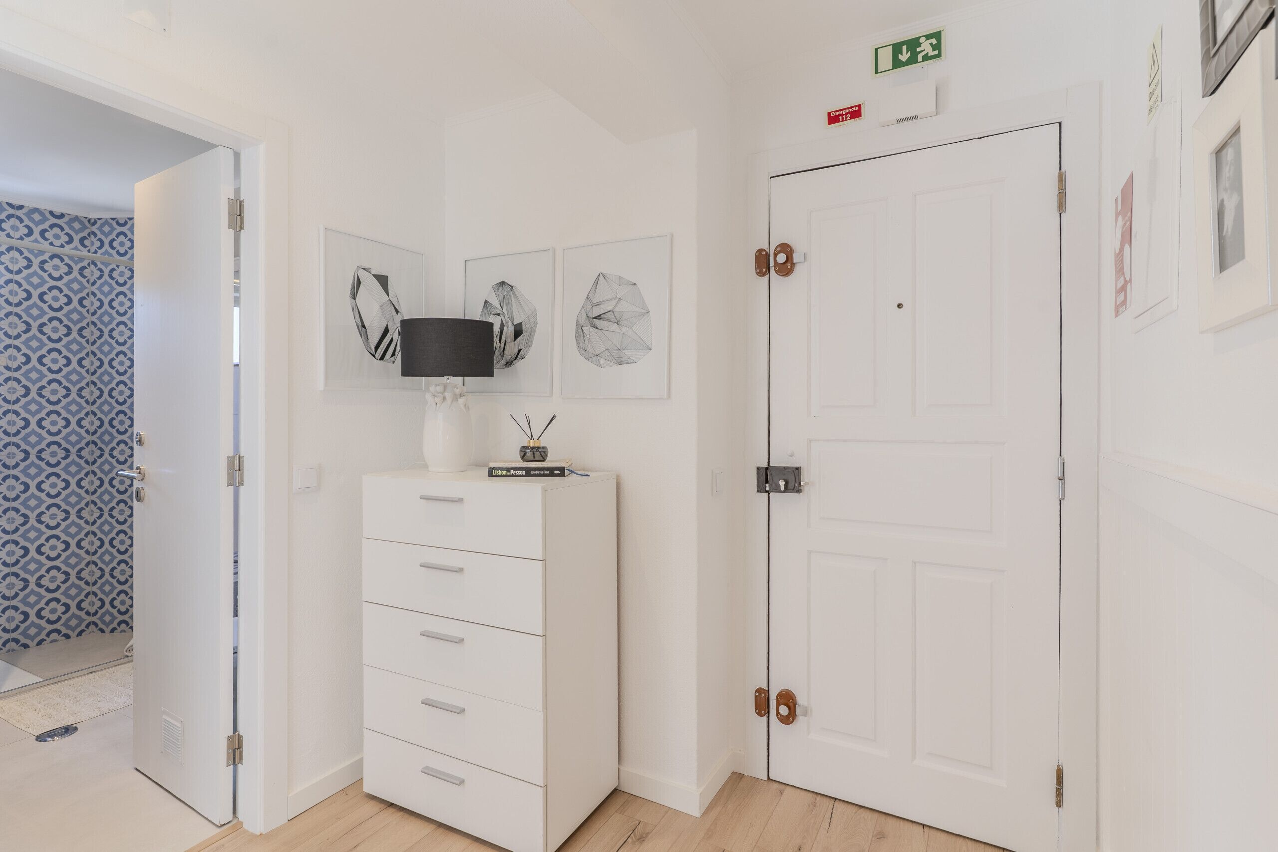 A room with a white wardrobe, a flat-screen TV, and a door with a green exit sign.
