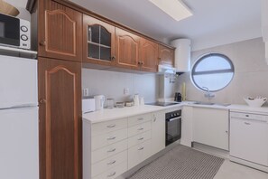 Eine moderne Küche mit Holzausstattung, einer weißen Arbeitsplatte, einem Einbauofen und einem Fenster.