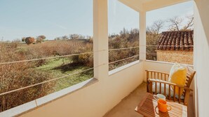 Un balcone con vista su un vigneto, una sedia di legno e un tavolo con una tazza.