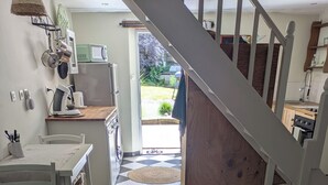 Une cuisine avec un carrelage à motifs, une table à manger, des chaises, un tapis et un escalier menant à une autre pièce.