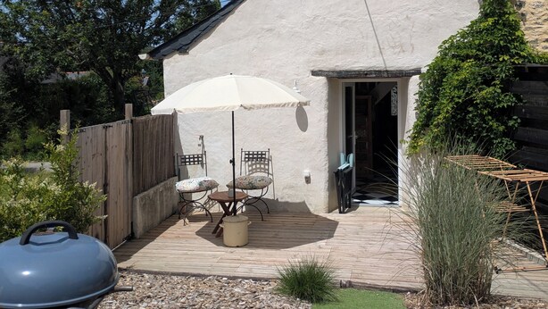 Une terrasse avec un barbecue, du mobilier d’extérieur et un petit coin jardin.
