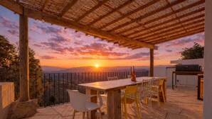 A patio with a table and chairs, a grill, and a view of the sunset. - Heated Plunge Pool | Mountain View’s (Málaga)