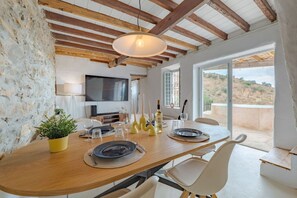 A dining area with a wooden table, chairs, a TV, and a view of the outdoors. - Heated Plunge Pool | Mountain View’s (Málaga)