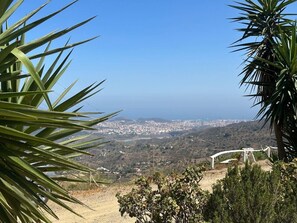 Eine Küstenlandschaft mit freiem Blick auf das Meer, einer entfernten Stadt und einer weißen Struktur im Vordergrund.