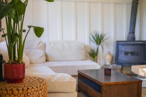 A living room with a white sofa, a wooden coffee table, and a red potted plant. - Heated Pool | Villa with Mountain View (Málaga)