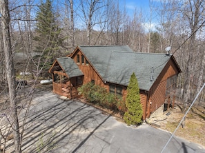 A log cabin with a porch, a chimney, and a small garden. - The Toasted Turkey (Gatlinburg)