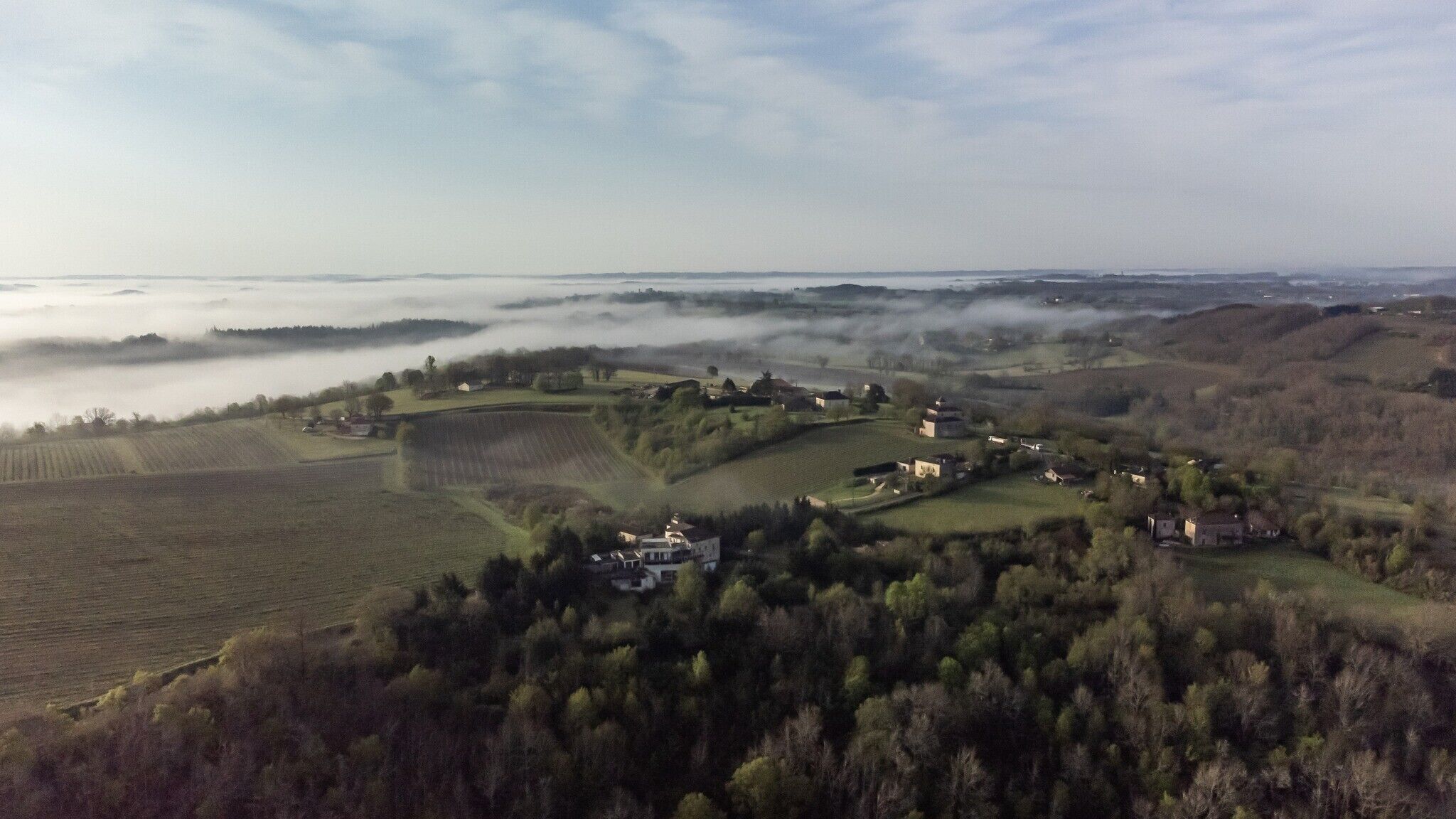 Un paysage rural caractérisé par des collines douces, des champs et des maisons dispersées.