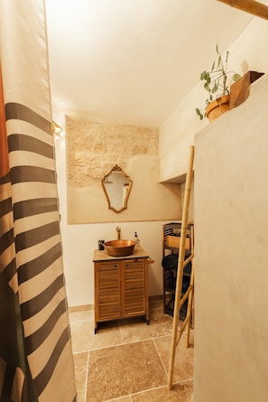 Ein Badezimmer mit einem Holzkabinett, einem Spiegel und einer Pflanze an der Wand.