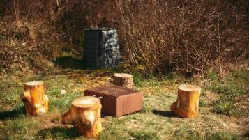 A grassy area with four wooden stumps and a metal box.