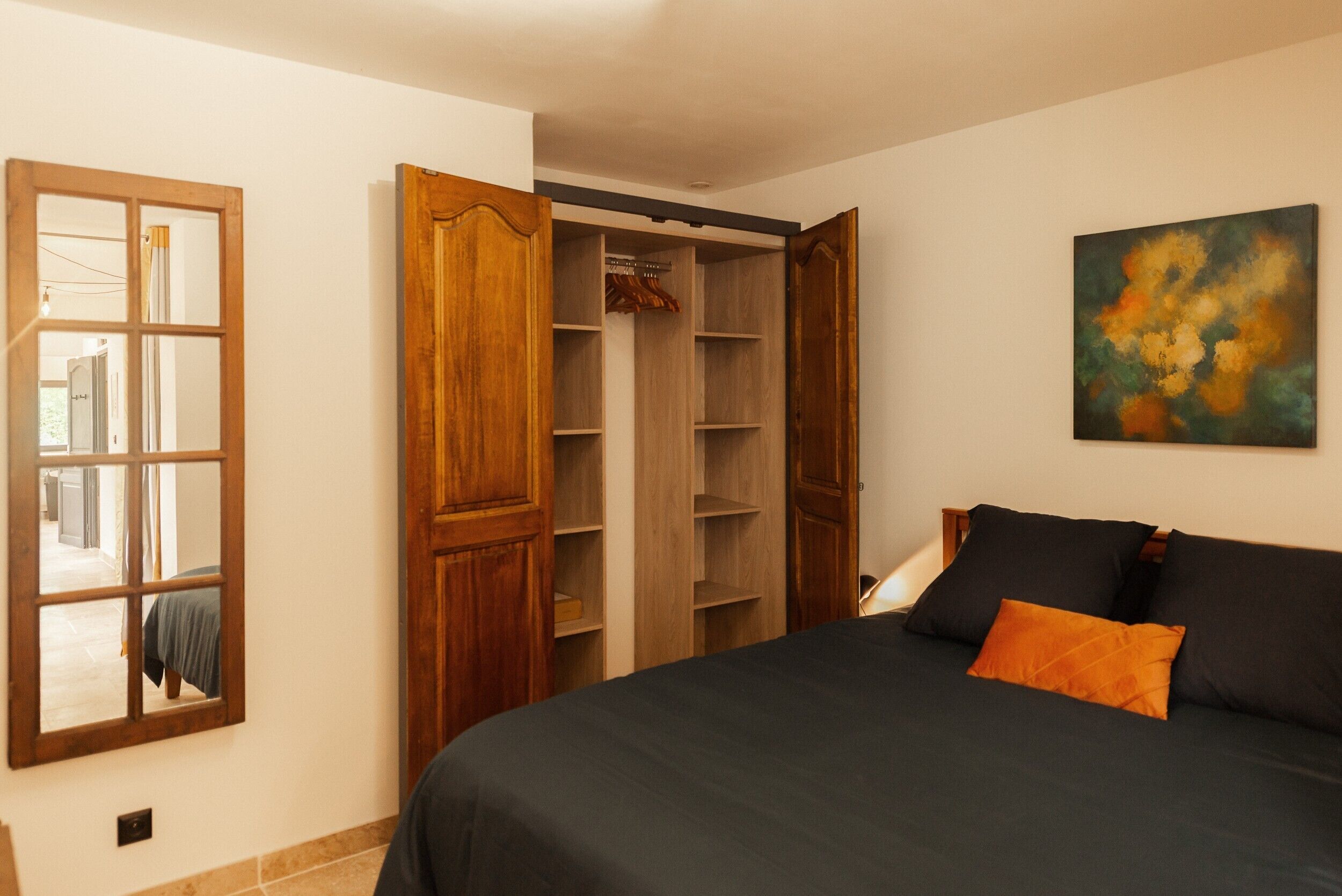 A bedroom with a bed, a wardrobe, and a painting on the wall.