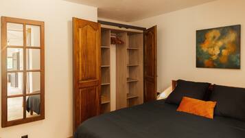 A bedroom with a bed, a wardrobe, and a painting on the wall.