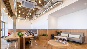 A modern interior with a wooden dining table, chairs, a sofa, and a small round table. - Station Noir Stylish 1-bed in Central MK (Milton Keynes)