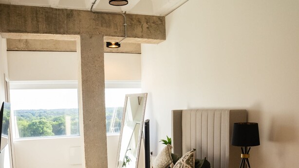 A bedroom with a bed, bedside table, lamp, and a view of greenery through a window. - Station Noir Stylish 1-bed in Central MK (Milton Keynes)