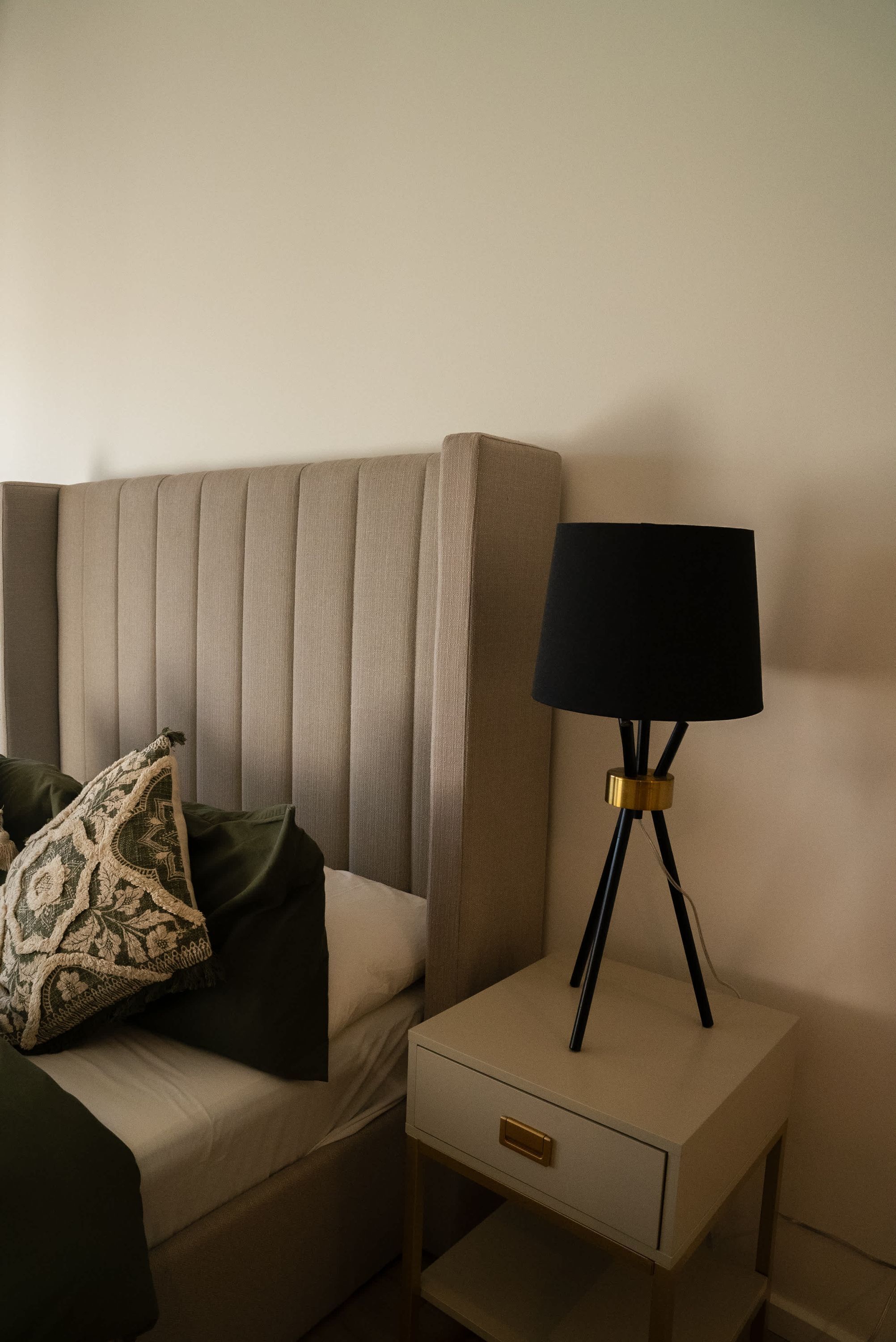 Un letto con testiera, un comodino con una lampada e un cassetto.