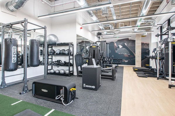 A gym with weightlifting equipment, treadmills, and a mirrored wall.