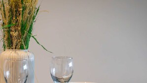 A dining table set with white bowls, a wine glass, and a vase with dried plants. - Station Elan Sleek 2-bed Apartment in Central MK (Milton Keynes)