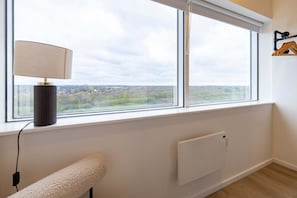 A room with a window, a radiator, a bench, and a lamp.