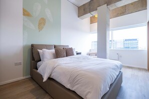 A modern bedroom with a large bed, a city view, and a concrete ceiling. - Station Gold Leaf Premium 1-bed Above MK Station (Milton Keynes)