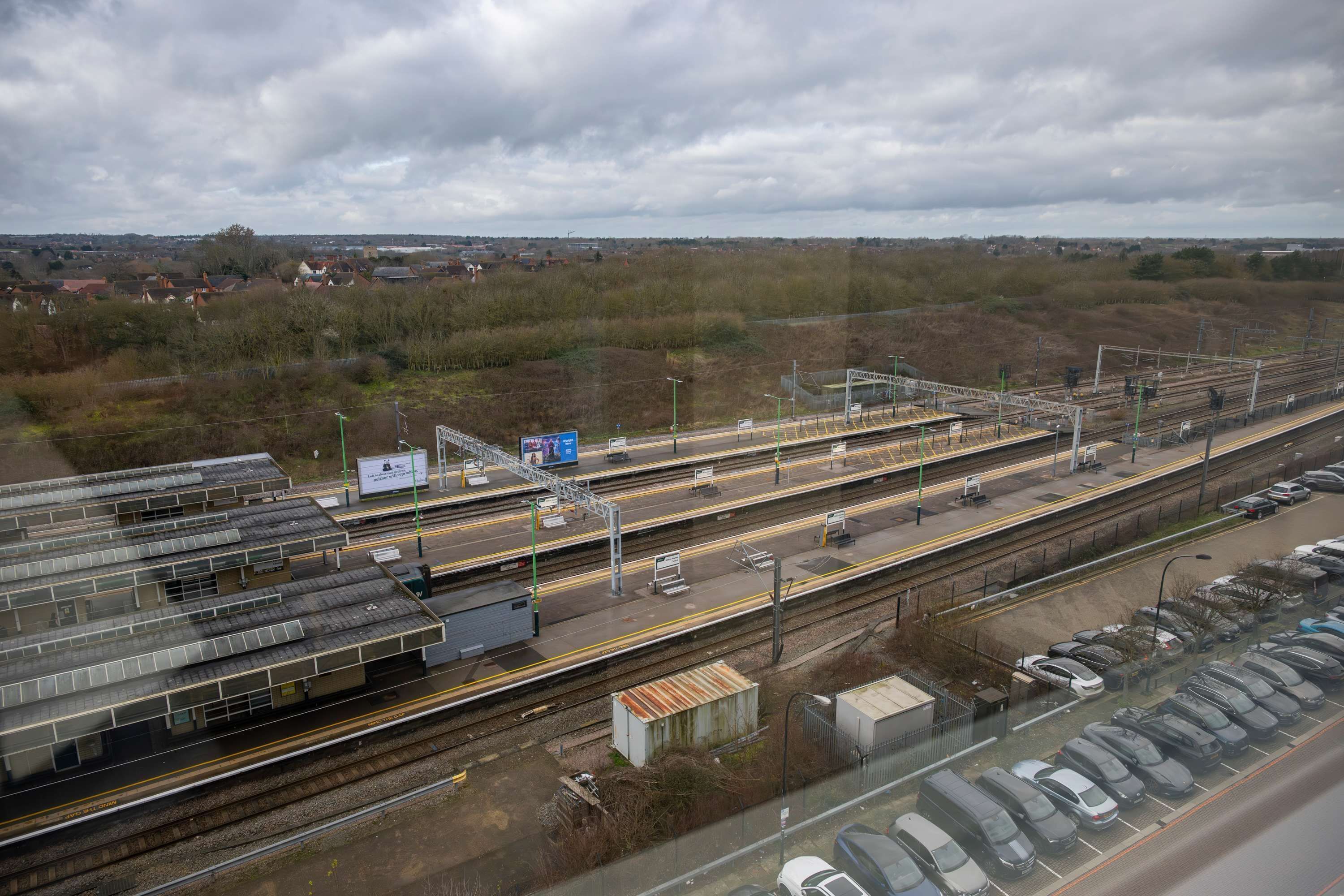 Ein Bahnhof mit mehreren Gleisen, einem Bahnsteig und einem Parkplatz.