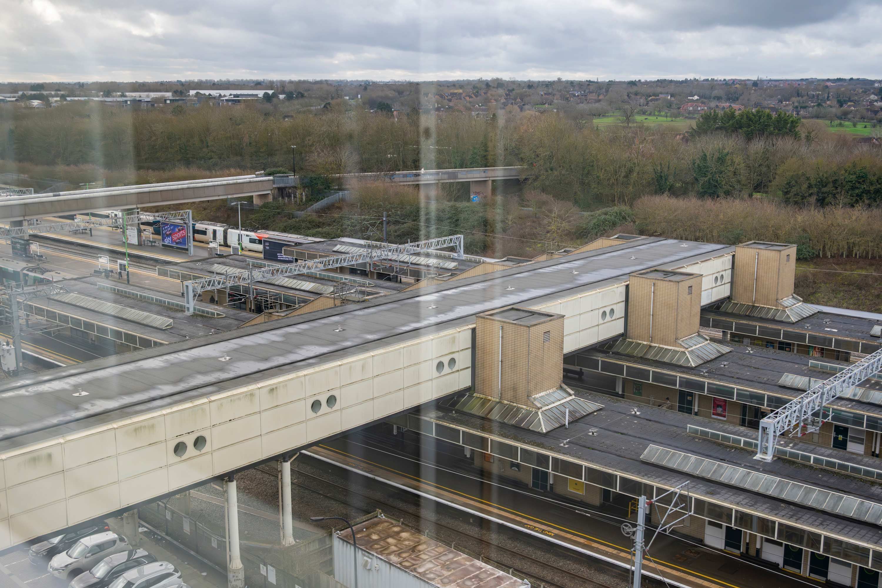 A train station with multiple platforms, a bridge, and a distant town.