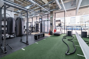 A gym with weightlifting equipment, treadmills, and a green artificial turf floor.