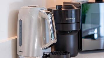 A Breville coffee maker, a Nespresso capsule machine, and a paper towel dispenser on a countertop.