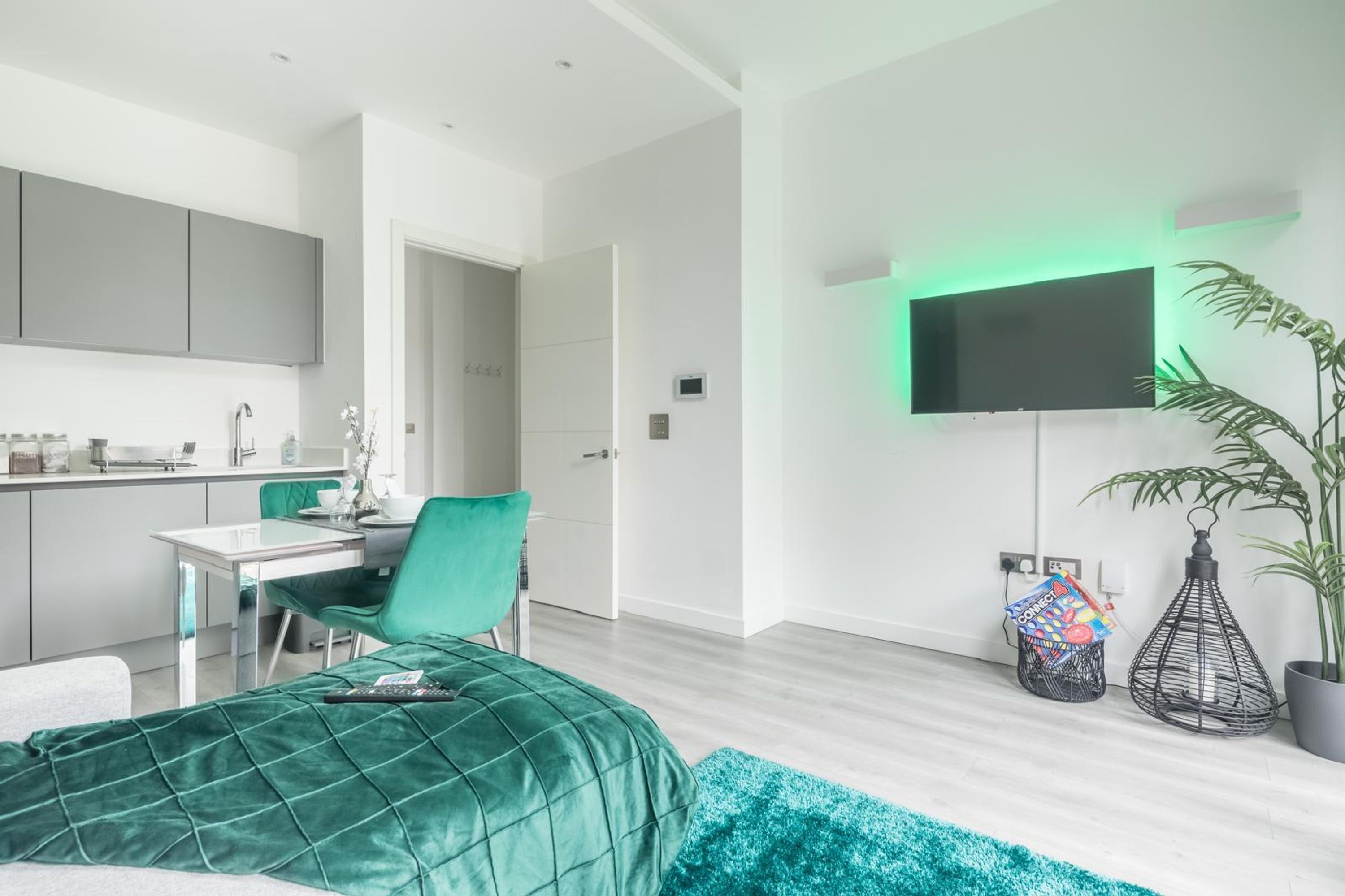 A modern bedroom with a bed, a desk, and a TV mounted on the wall.