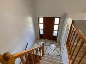 A staircase with wooden railings leading to a door with a stone floor. - Spacious, Charming & Serene Family Haven ~ Parking (Kingsport)