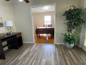 A room with a desk, a potted plant, and a dining area with a table and chairs. - Spacious, Charming & Serene Family Haven ~ Parking (Kingsport)