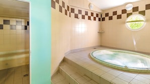 Ein Badezimmer mit Badewanne, gefliesten Wänden, einem Fenster und einer Dusche.
