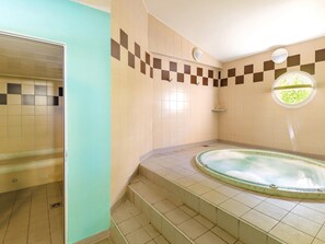 Ein Badezimmer mit Badewanne, gefliesten Wänden, einem Fenster und einer Dusche.