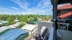 Un balcone con vista su una zona residenziale, con case dai vari colori del tetto e un cielo sereno.