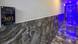 Un corridoio con una insegna che indica 'OLYMPIADA GIRNI 301 APARTMENT' e un pavimento in marmo.