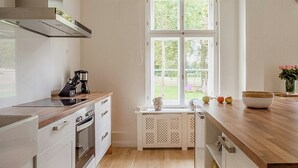 Una cocina moderna con una isla central, horno empotrado y un amplio ventanal con vistas a zonas verdes.