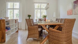 Un comedor con sillas de mimbre, una mesa de madera y una estantería.