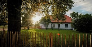 Ein weißes Haus mit rotem Dach, umgeben von einem Holzzaun und Bäumen.
