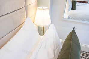 A neatly made bed with white linens, a bedside lamp, and a green pillow. - Studio Retreat in Islington (Greater London)
