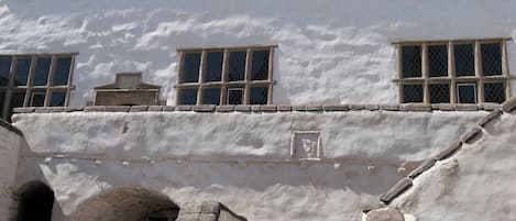 Un edificio con varias ventanas, un arco de piedra y una puerta pequeña.