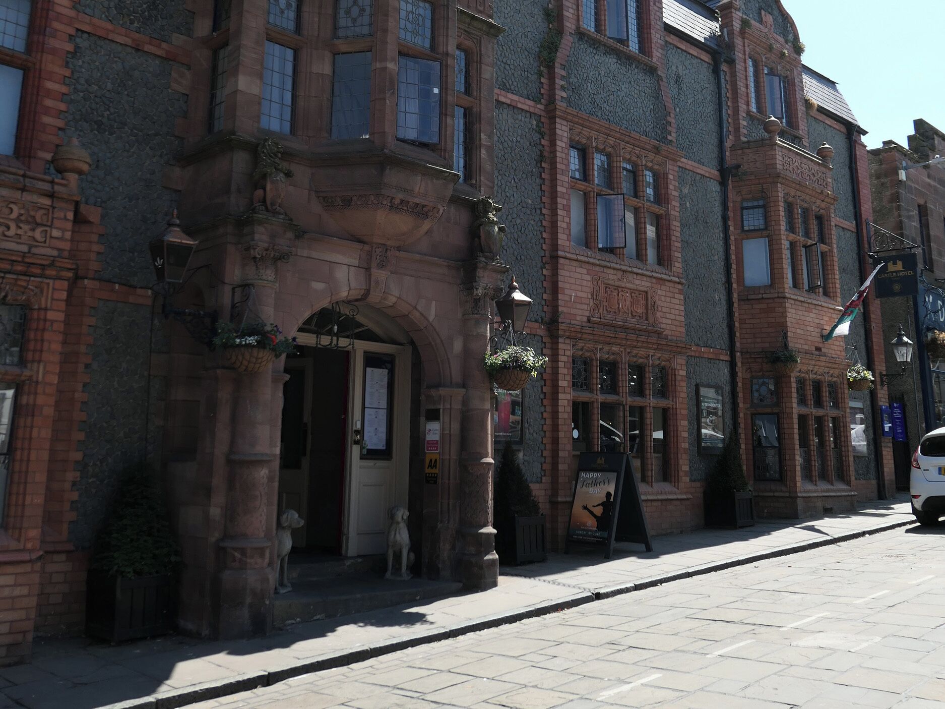 A historic building with a prominent entrance, a signboard, and a flag.