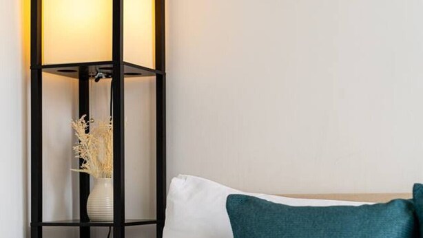 A bed with white linens and teal pillows, a black floor lamp with a vase of dried flowers, and a painting on the wall. - West Hampstead Hub - 1 bedroom spacious apartment (Greater London)