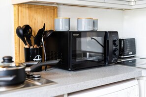 Eine Küche mit einer schwarzen Sharp-Mikrowelle, einer Kaffeemaschine und einem Toaster.